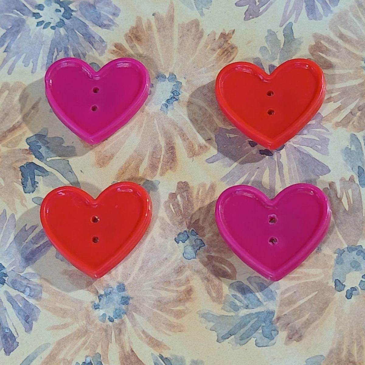 Four heart-shaped buttons in two shades of pink and two shades of red
